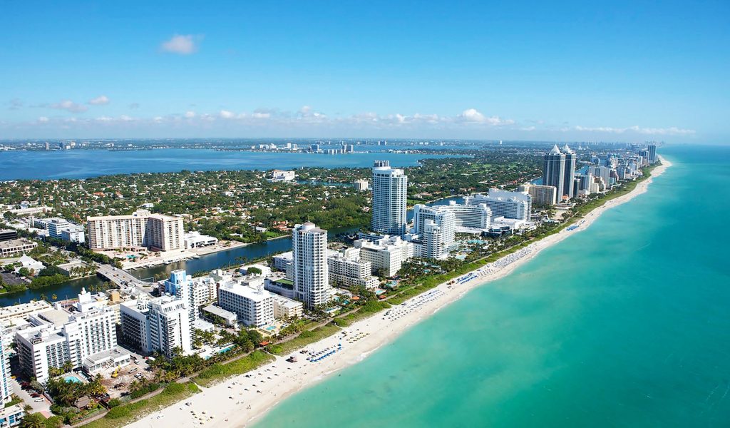 Aerial view of stunning buildings next to a white beach at Miami Beach ...